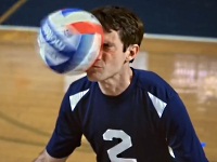 バレーボールの試合で相手のアタックを顔面レシーブする男性